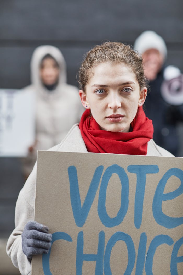 Focused woman participates in a peaceful protest with a 'Vote Choice' placard.